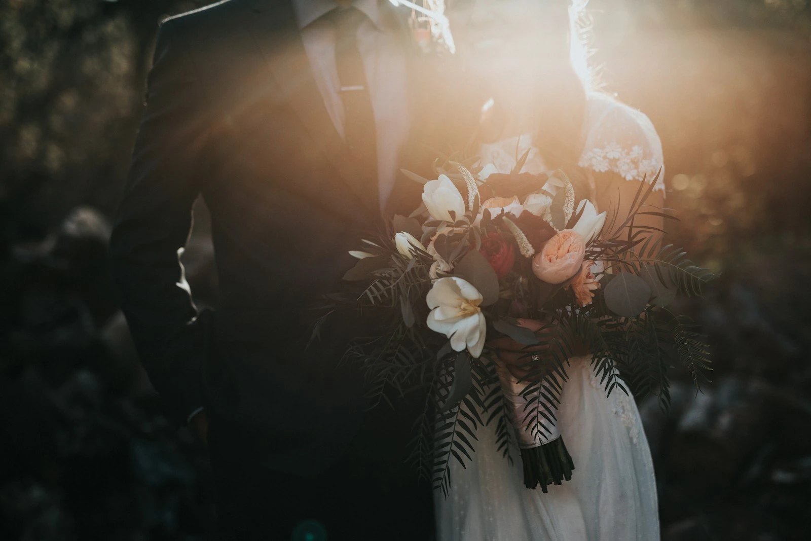 A bride and groom with a bouquet in warm sunlight