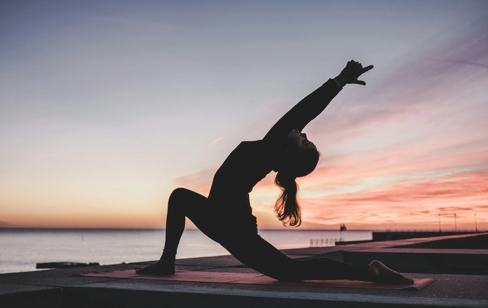 A silhouette in a yoga lunge against a sunset sky