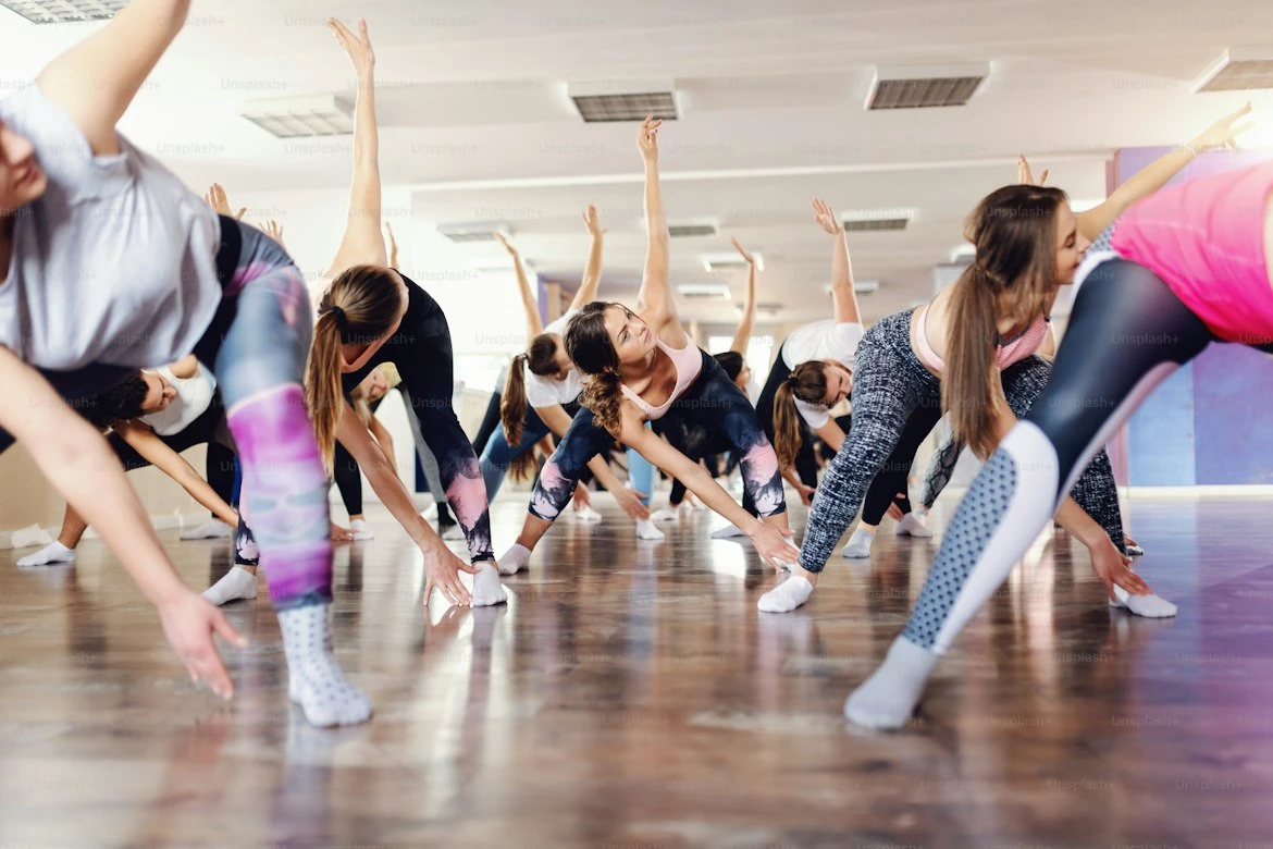 A group stretching together in a bright dance studio