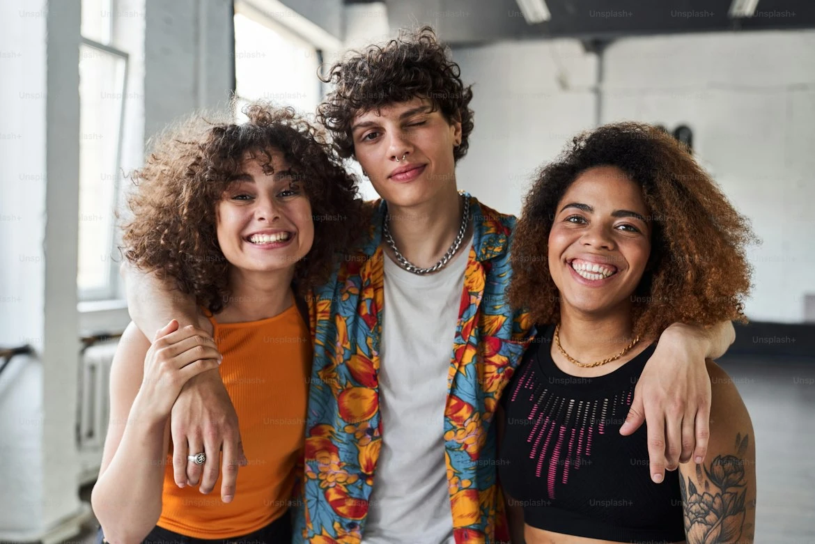 Three smiling friends with their arms around each other