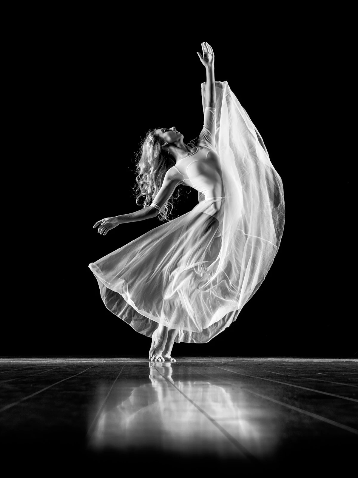 A dancer in a flowing white dress in black and white